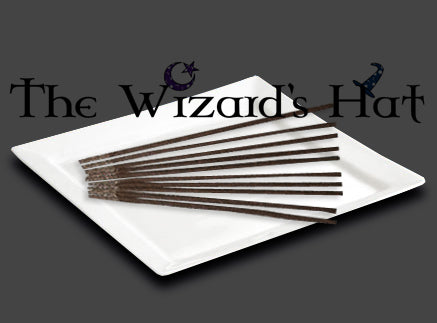White plate with black incense sticks on a dark background, featuring 'The Wizard's Hat' branding.