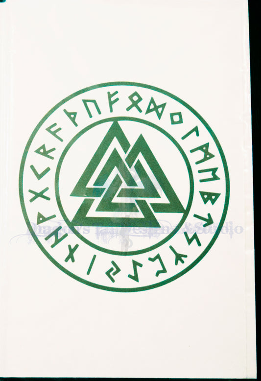 A square white item featuring a green circular Norse-style emblem with a central interwoven triangle and runes around the border, photographed against a dark background.